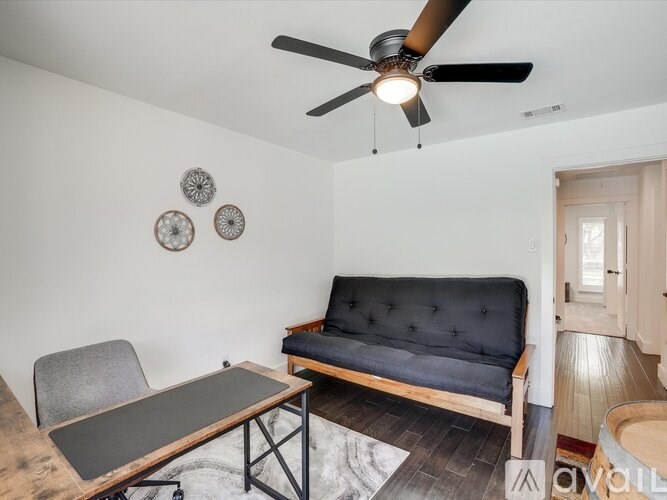 A living room with a black couch, a grey chair, and a wooden coffee table.