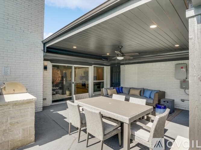 A patio with a table and chairs is covered by a roof.
