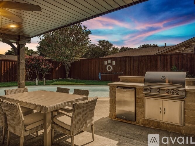 A patio with a table, chairs, and an outdoor kitchen.