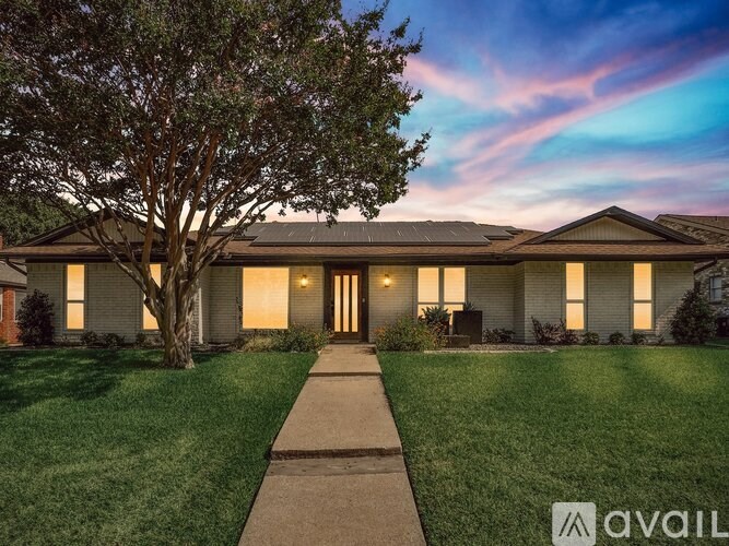 A house with a tree in front and a walkway leading to the front door.