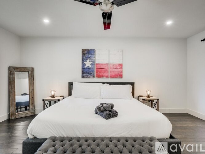 A bedroom with a large bed and a Texas flag on the wall.