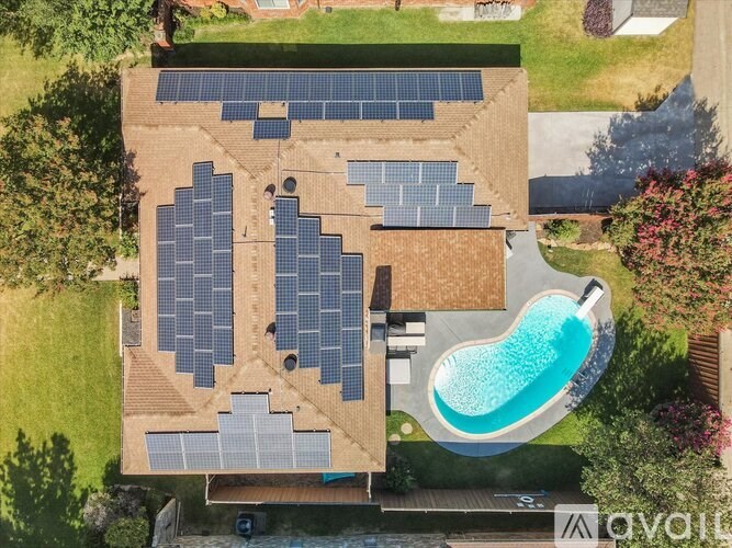 A house with solar panels on the roof and a pool in the backyard.