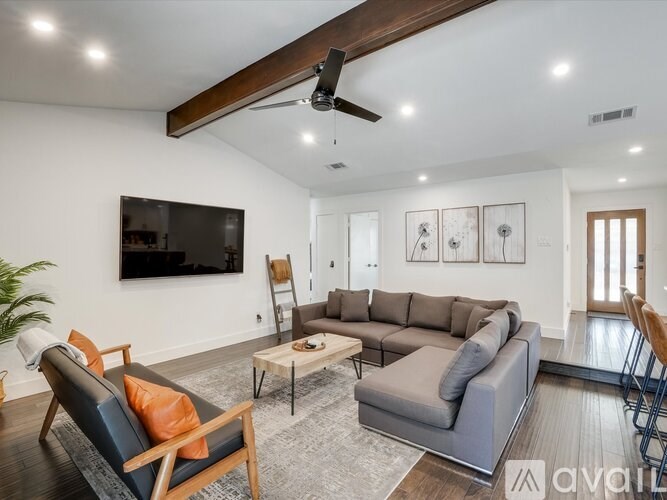 A living room with a grey sofa, a black leather chair, and a wooden coffee table.