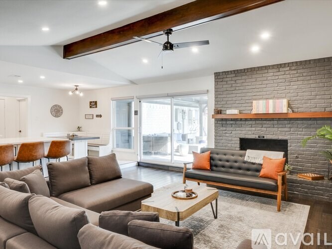 A living room with a grey couch and a black fireplace.