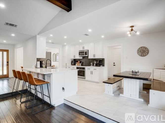 A modern kitchen with white cabinets and a wooden island.