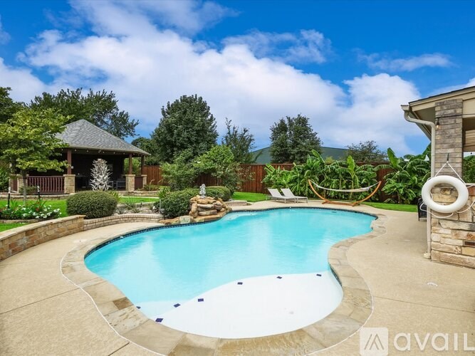 A swimming pool surrounded by a stone wall and a gazebo.