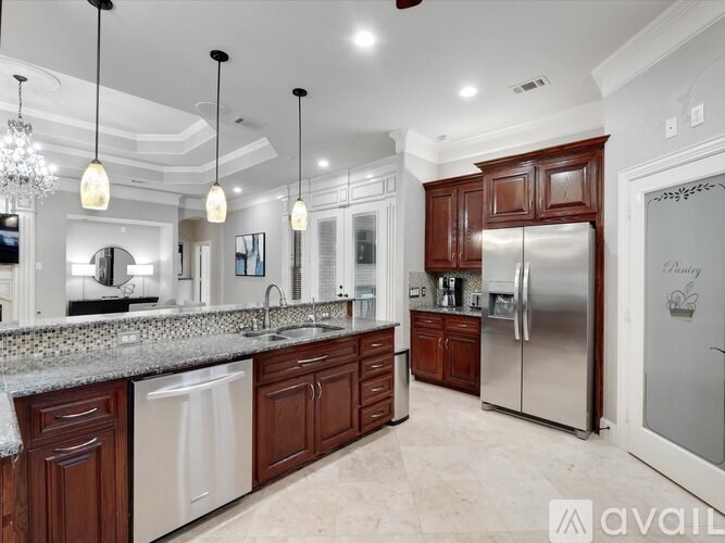 A kitchen with a refrigerator, sink, and cabinets.