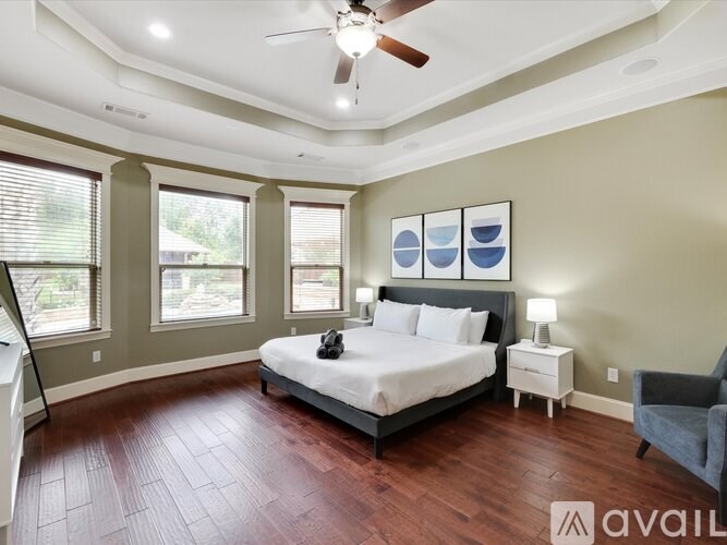 A bedroom with a bed, a nightstand, a chair, and a ceiling fan.