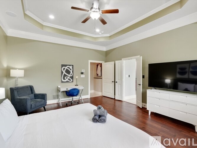 A bedroom with a large bed, a ceiling fan, and a television.