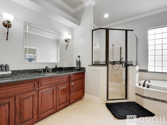 A bathroom with a large mirror, wooden cabinets, and a glass shower stall.