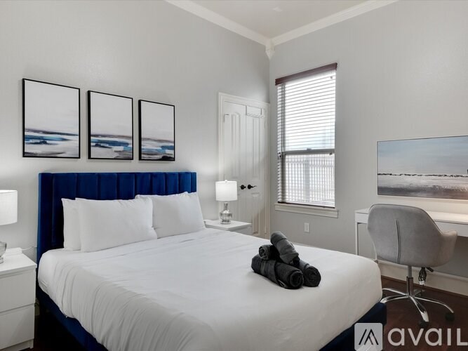 A bedroom with a large bed, a chair, and a desk with a computer.