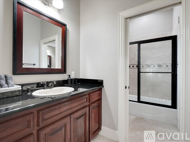 A bathroom with a sink, mirror, and a window.