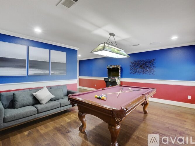 A pool table is in the middle of a room with a couch and a window.