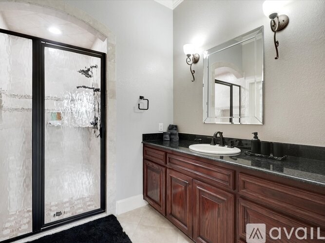 A bathroom with a sink, mirror, and a glass door.
