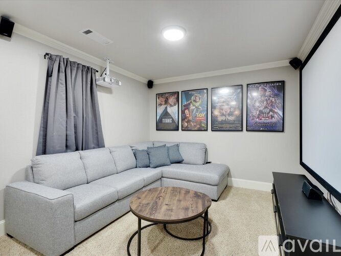 A living room with a grey couch, a coffee table, and a wall with framed pictures.