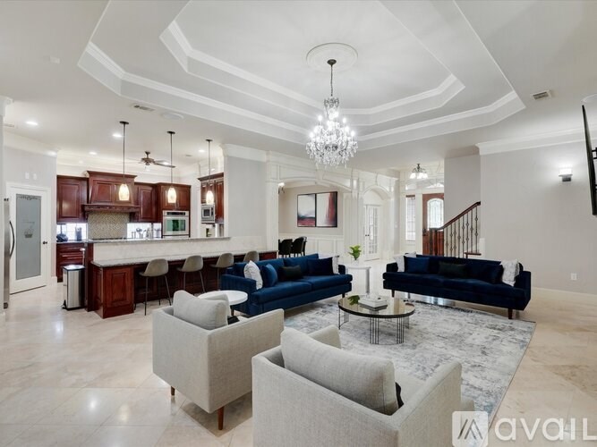 A spacious living room with a kitchen area in the background.