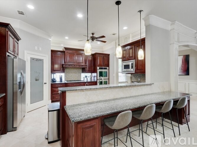 A kitchen with a marble countertop and wooden cabinets.