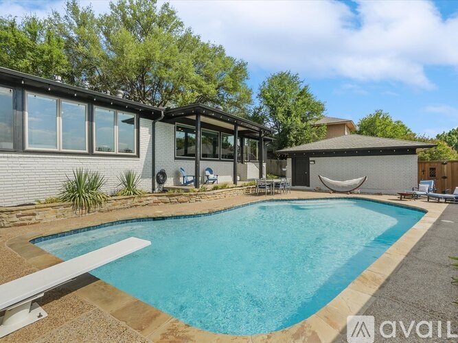 A pool in a backyard with a house and trees in the background.