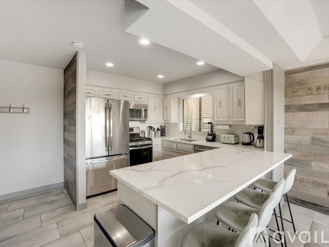 A modern kitchen with a white marble countertop and stainless steel appliances.