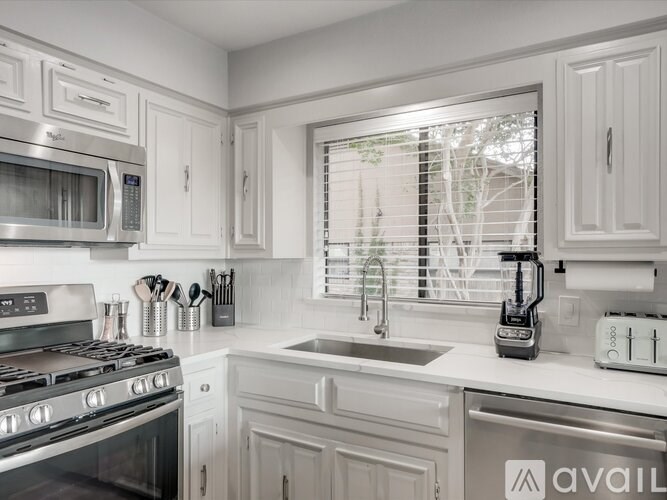 A modern kitchen with white cabinets and stainless steel appliances.