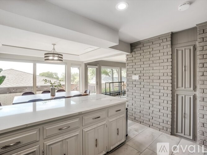 A kitchen with a white countertop and a brick wall.