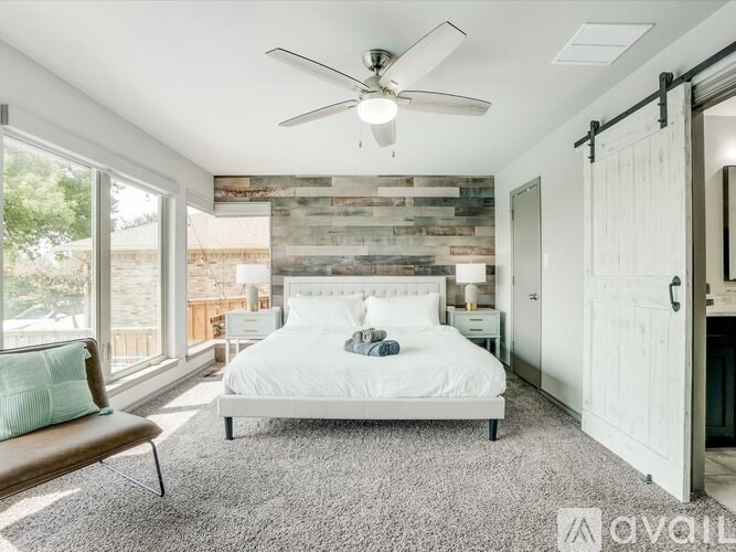 A bedroom with a bed, a bench, and a ceiling fan.