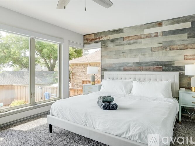 A bedroom with a white bed and a wooden wall.