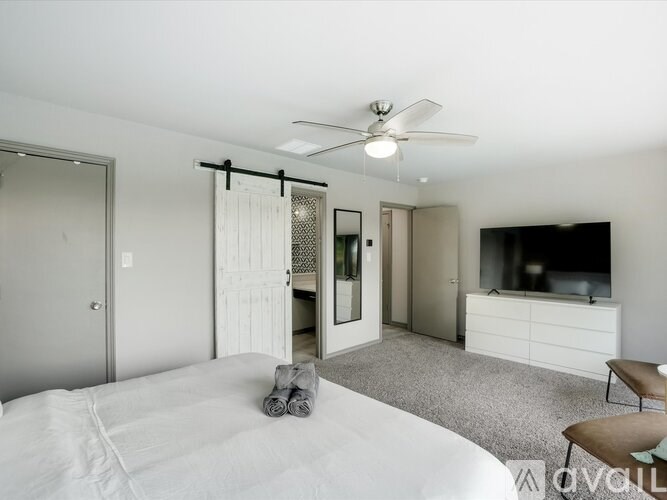 A bedroom with a bed, a chair, and a television.