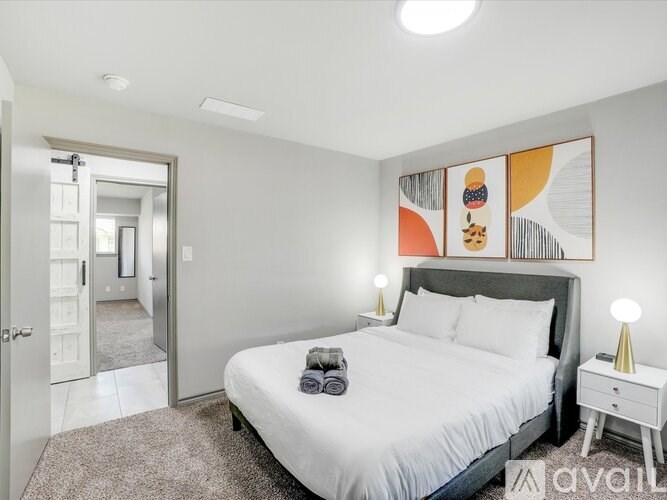 A bedroom with a large bed, a nightstand, and a painting on the wall.