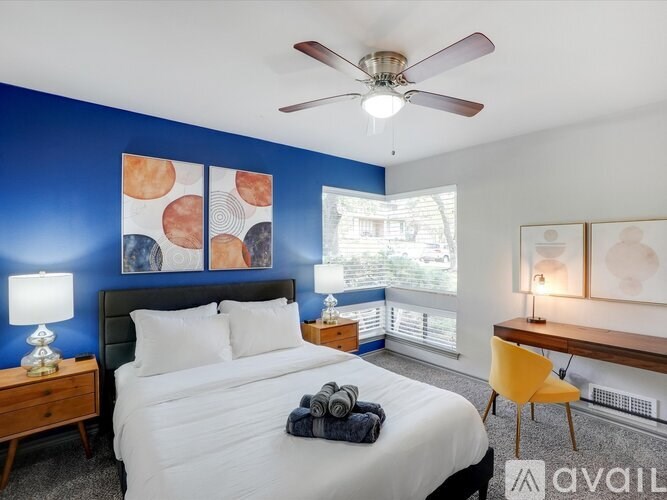 A bedroom with a bed, a chair, and a ceiling fan.