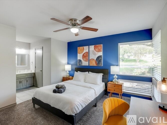 A bedroom with a bed, a chair, and a ceiling fan.