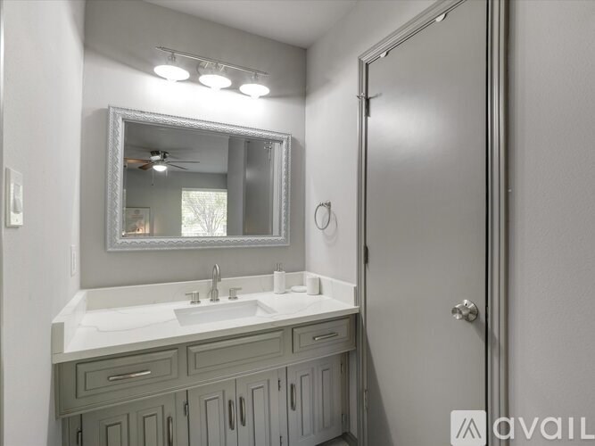 A bathroom with a sink, mirror, and cabinets.