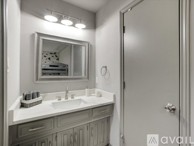 A bathroom with a sink, mirror, and a towel rack.
