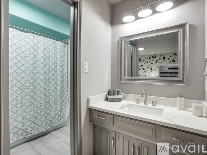 A bathroom with a mirror, sink, and shower.