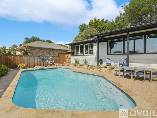 A swimming pool in a backyard with a house and a fence.