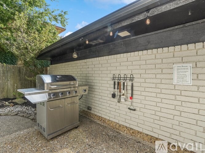 A BBQ grill is placed outside a building with a sign on the wall.