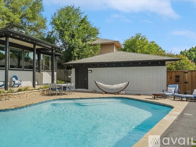 A pool with a hammock and a house in the background.