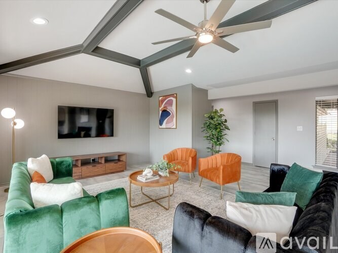 A living room with a green couch, orange chairs, and a ceiling fan.