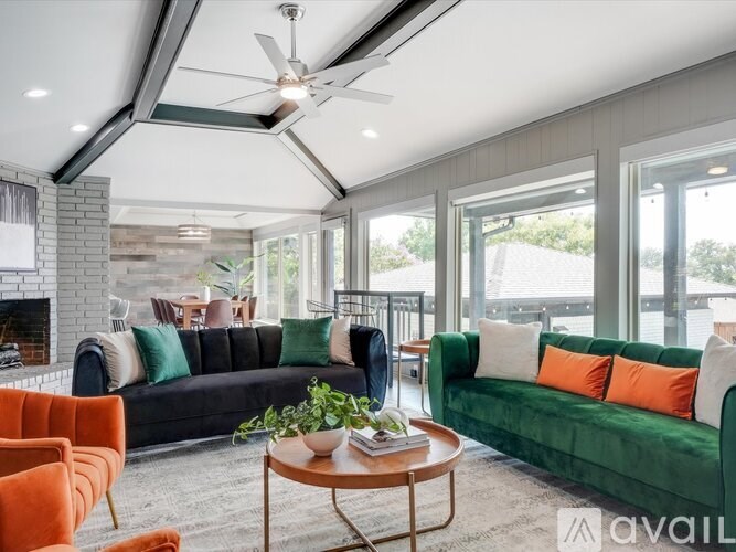 A living room with a black couch, orange chairs, and a coffee table.
