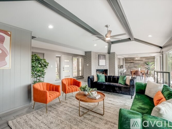 A living room with a green couch, orange chairs, and a coffee table.