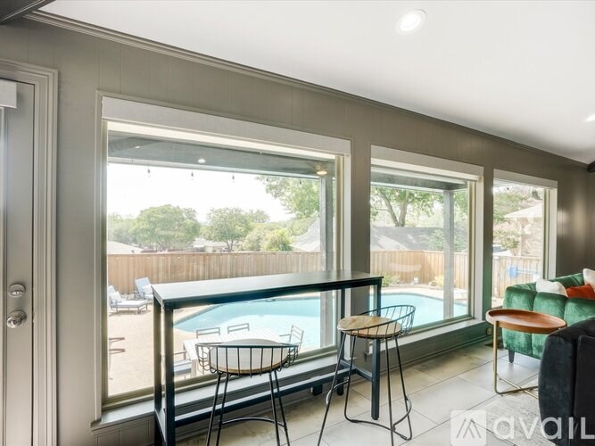 A balcony with a table and chairs overlooks a pool.