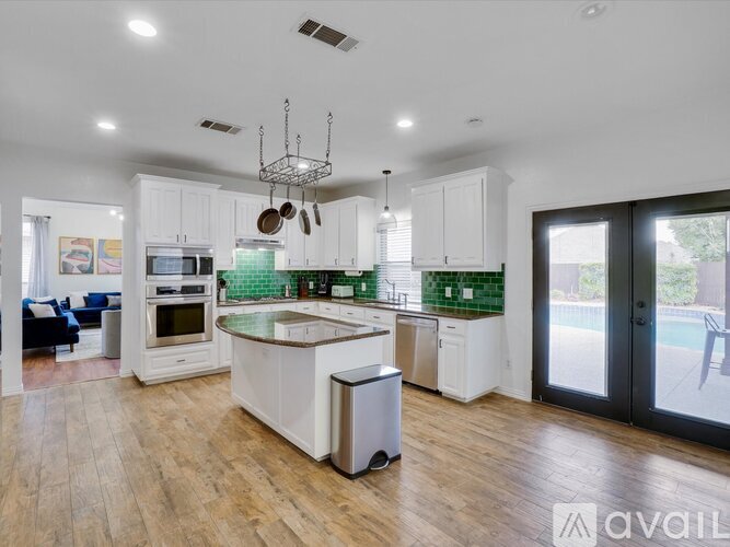 A modern kitchen with white cabinets and a wooden floor.