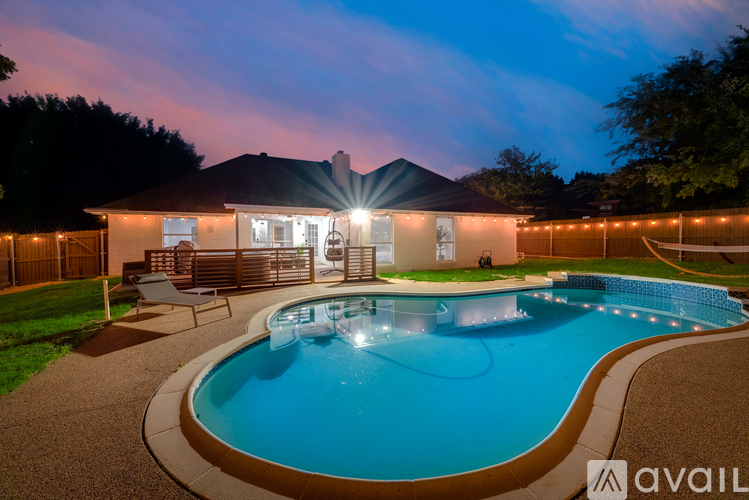 A house with a pool in the backyard at night.