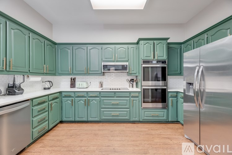 A kitchen with green cabinets and stainless steel appliances.