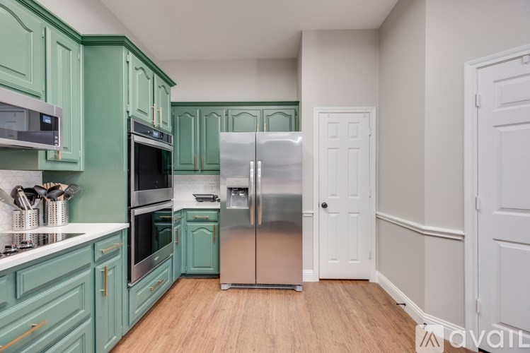A kitchen with green cabinets and a stainless steel refrigerator.