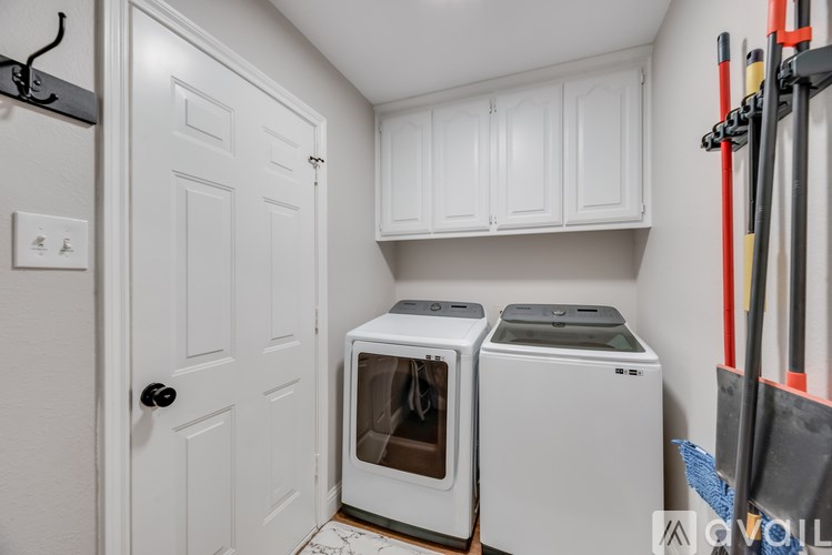 A white kitchen with a white door, white cabinet, and two white microwaves.