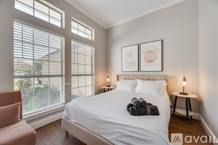 A bedroom with a large bed, a chair, and two framed pictures on the wall.