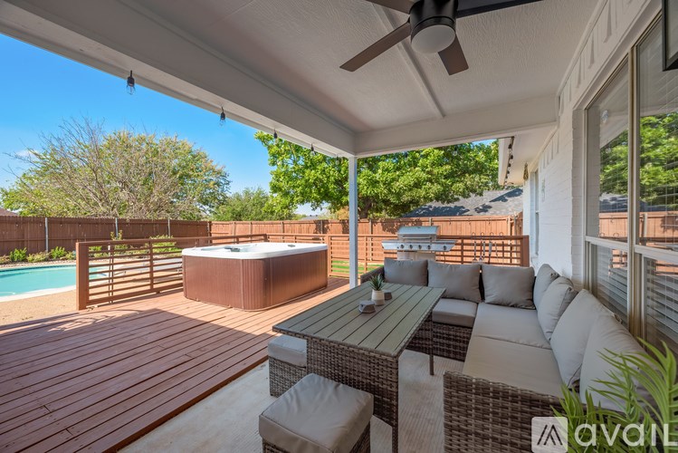 A patio with a hot tub and a table with chairs.