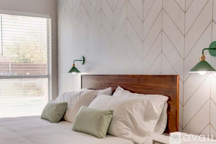 A bedroom with a large bed and two green lampshades.