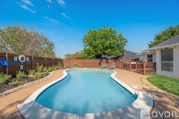 A small residential pool surrounded by a wooden fence and a tree.